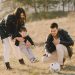 A happy family playing with a soccer ball in a grassy field on a sunny day.