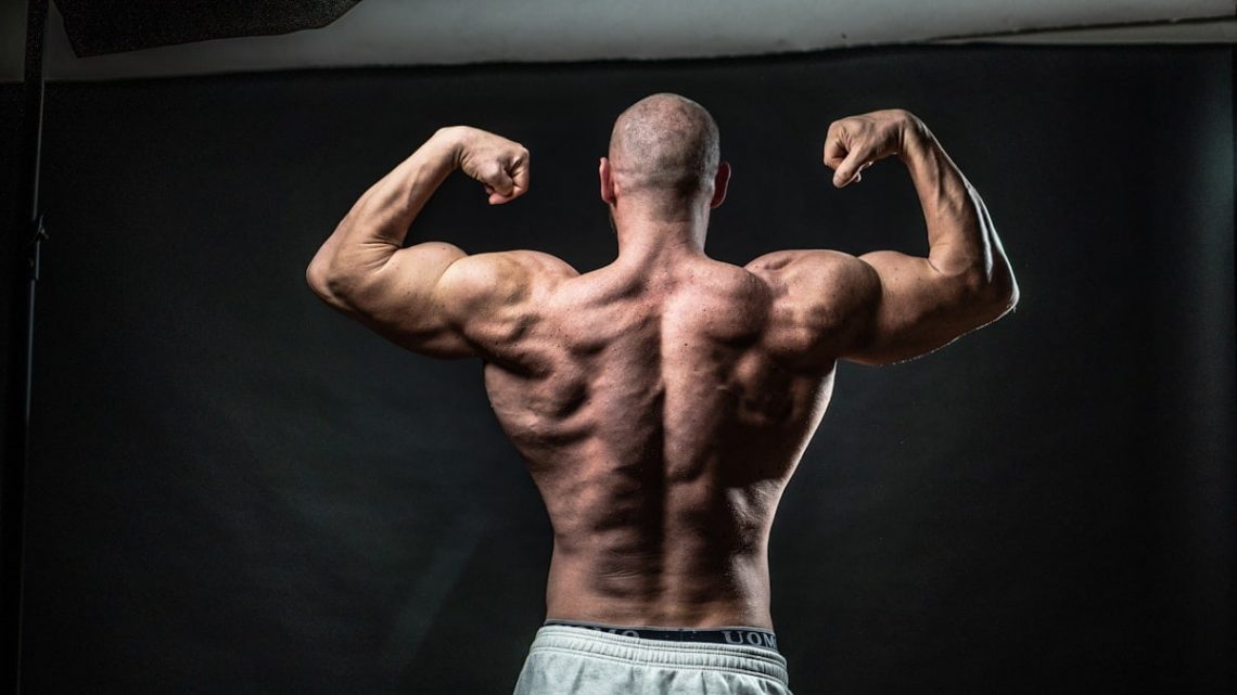 a man flexing his muscles in front of a black background