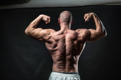 a man flexing his muscles in front of a black background