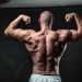 a man flexing his muscles in front of a black background